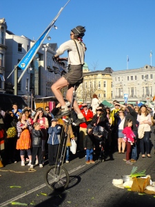 Street performer playing the horns while riding a giant unicycle